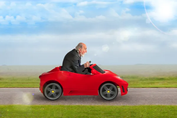 Senior homem dirigindo um carro de corrida de brinquedo Fotos De Bancos De Imagens
