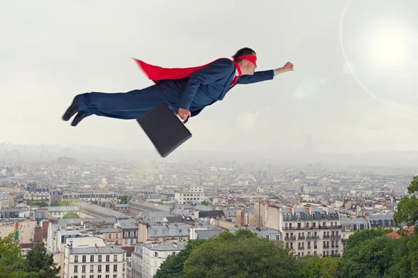 Super-herói empresário voando acima de uma cidade Fotos De Bancos De Imagens