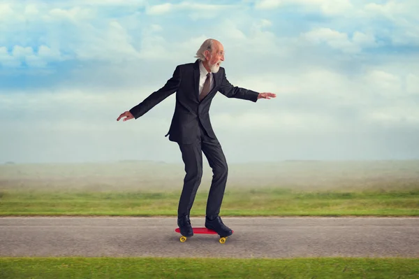 Äldre man rida en skateboard Stockbild