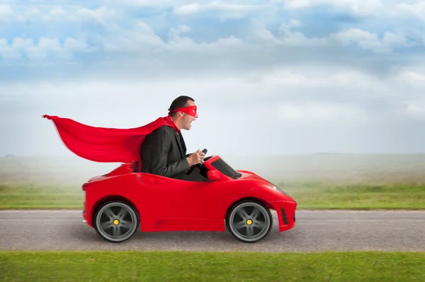 Super herói homem dirigindo um carro de corrida de brinquedo — Fotografia de Stock