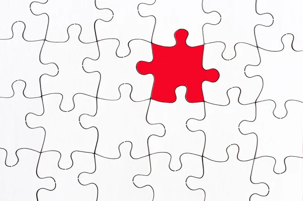 Jigsaw branco em branco com uma peça vermelha — Fotografia de Stock