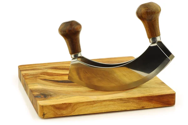 Modern herb cutter (wiegemes) with wooden handles on a wooden cutting board — Stock Photo, Image