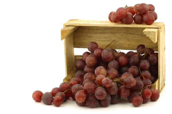 Свежий красный виноград на виноградной лозе в деревянном ящике — стоковое фото