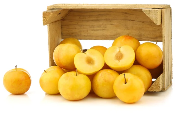 Yellow plums and a cut one in a wooden crate — Stock Photo, Image