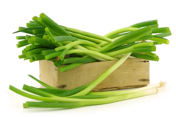 Bos van groene uien in een houten krat — Stockfoto