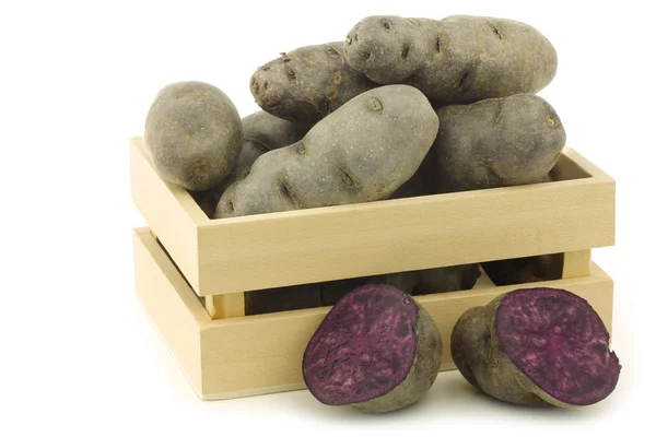 Batatas de trufa roxas e um corte em uma caixa de madeira — Fotografia de Stock