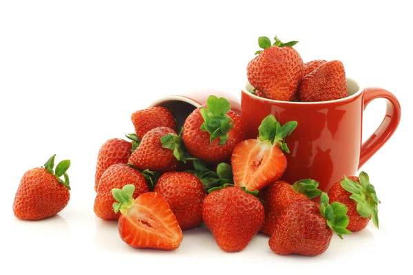 Fresh strawberries and a cut one in red ceramic cups — Stock Photo, Image