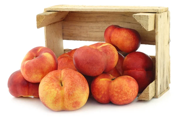 Fresh wild (flat) nectarines in a wooden crate — Stock Photo, Image