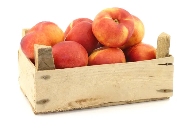 Fresh wild (flat) nectarines in a wooden crate — Stock Photo, Image