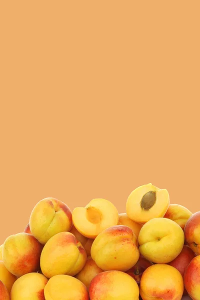 Fresh colorful apricots and a cut one on a orange background — Stock Photo, Image