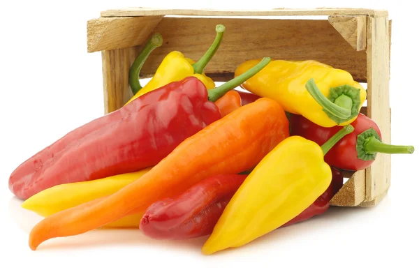 Rood, geel en oranje scherpsmakende pepers (paprika) in een houten krat — Stockfoto