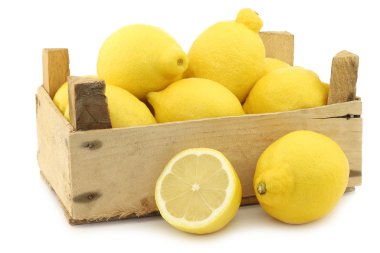 Fresh lemons and a cut half in a wooden crate clipart