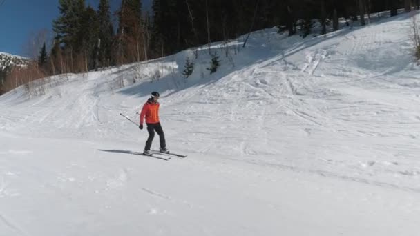En skidåkare rullar nerför berget Pushing Off med pinnar för att få fart — Stockvideo