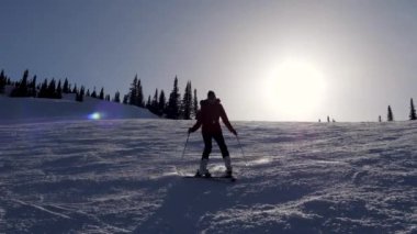 Kışın güneşli bir günde dağ yamacında kayak yapan dağ kayakçısı.