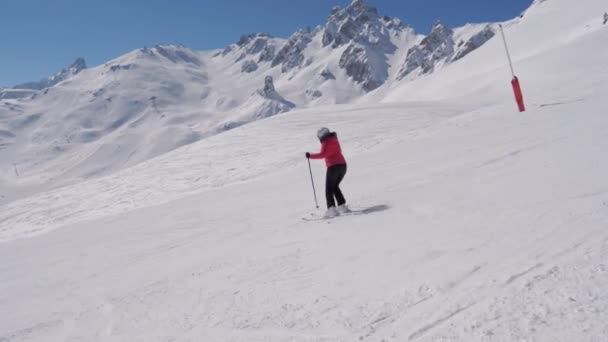 Яркий лыжник спускается по снежному склону в горах зимой на лыжах — стоковое видео