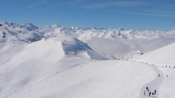 Veel skiërs en snowboarders glijden van de skipiste in de besneeuwde bergen in de winter — Stockvideo