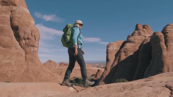 Turistická turistika na oranžových pískovcových skalních útesech v poušti při západu slunce — Stock video
