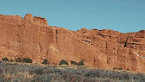 Piros narancs monolitikus sziklák kialakulása száraz sivatagban napsütéses napon mozgásban — Stock videók