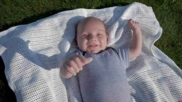 Smiling Newborn Baby Is Lying On Blanket On Green Lawn Outdoor — Stock Video