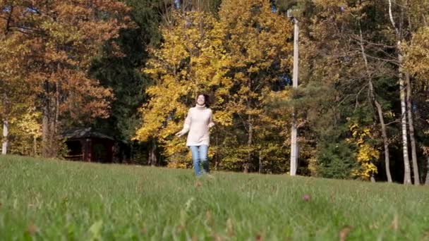Glad kvinna glatt kör över grön gräsmatta med händerna upphöjda till sidan — Stockvideo