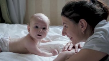 Kafkasyalı anne, yeni doğmuş bebeğiyle konuşuyor. Yatakta yatıyor.