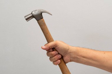 Adamın eli gri arkaplanda izole edilmiş bir araç tutuyor.