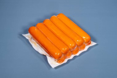 Mavi arka planda üretici tarafından plastiğe sarılmış sosis.