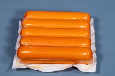Mavi arka planda üretici tarafından plastiğe sarılmış sosis.