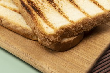 Tahtanın üstünde bir somun ekmek ve yeşil arka plan.