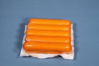 Mavi arka planda üretici tarafından plastiğe sarılmış sosis.