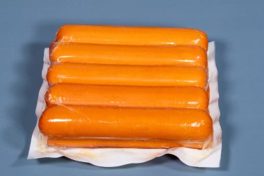 Mavi arka planda üretici tarafından plastiğe sarılmış sosis.