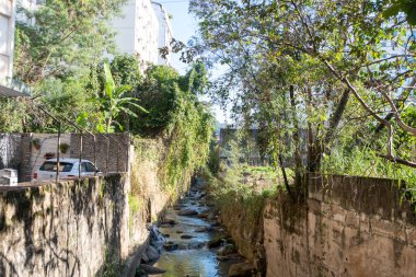 Rio, Brazil - July 05, 2022: view of the Maracana river which is degraded and polluted with trees around it in the Tijuca neighborhood