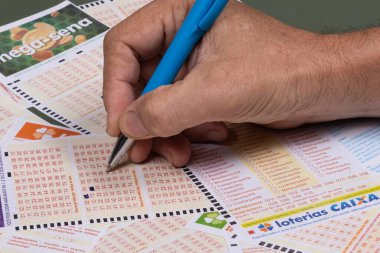 Rio, Brazil - July 20, 2022: person filling out Caixa Economica Federal lottery card, the only official betting method in Brazil
