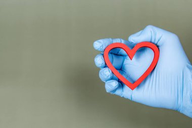 Cirurgical gloved hand holding a heart shape