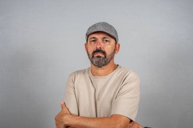 Çekici, olgun bir adamın portresi. Gri arka planda izole edilmiş bej gömlek giyen gerçek mutlu duygular hisset.