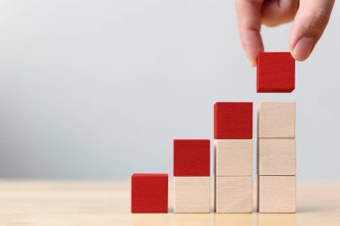 En üst basamakta kırmızı tahta bloğu tutan el. İş büyüme süreci için merdiven kariyer yolu kavramı