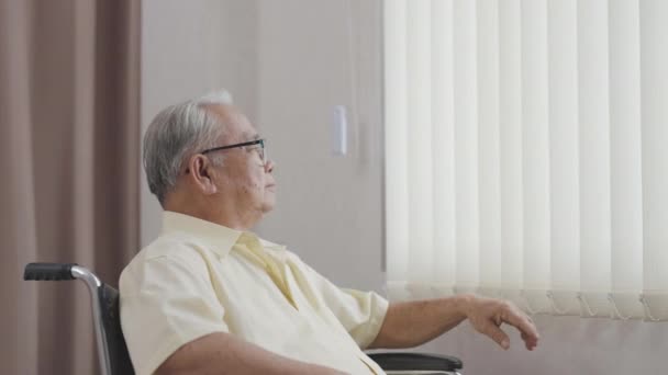 Stary Azjata Siedzi Wózku Inwalidzkim Patrzy Przez Okno Opieka Zdrowotna — Wideo stockowe