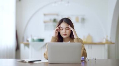 Ofis sendromu konsepti. Çok çalışan yorgun Asyalı kadın baş ağrısı çekiyor, bilgisayardan sonra görme sorunu yaşıyor. Evde yorgunluk çeken stresli bir iş kadını.