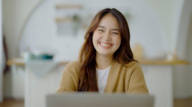 Kameraya bakan Asyalı genç bir kadının portresi. Yüz ifadesi mutlu.