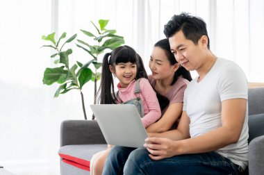 Mutlu Asyalı aile evde, oturma odasında birlikte oynuyor.