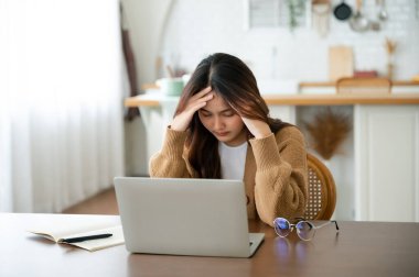 Ofis sendromu. Çok çalışan yorgun Asyalı kadın baş ağrısı çekiyor, bilgisayardan sonra görme sorunu yaşıyor. Stresli genç kadın evde yorgunluk çekiyor.