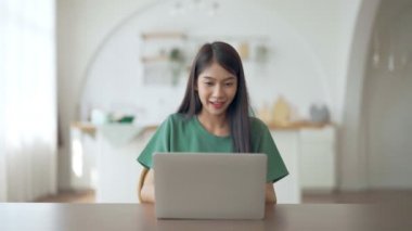 Asyalı bir kadının kazanmasını ya da bilgisayar laptopunda ecommerce alışveriş teklifi almasını kutlayan komik bir coşku. Heyecanlı mutlu kız kazanan başarıyı kutlayan deftere bakıyor.