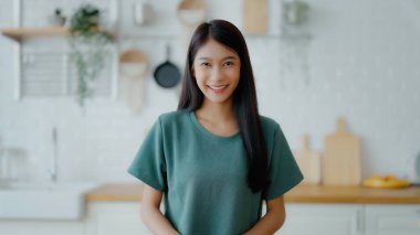 Kameraya bakan Asyalı genç bir kadının portresi. Yüz ifadesi mutlu.