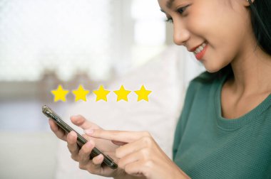 Müşteri hizmetleri tecrübesi ve iş memnuniyeti anketi. Şirketin konseptini yükseltmek için elinde simge olan akıllı telefon kullanan bir kadın.