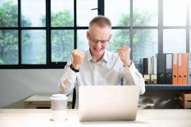 İş adamı online başarı kutlaması yapıyor, başarı elde ediyor, genç adam iyi e-posta haberlerinden memnun, büyük bir teklifle veya yeni bir fırsatla motive oluyor.