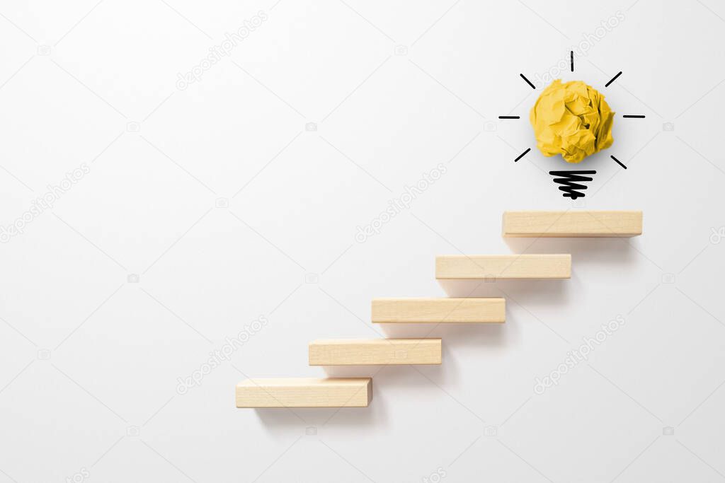 Concept creative idea and innovation. Paper scrap ball yellow colour with light bulb symbol on top step staircase growing growth