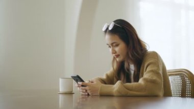 Genç Asyalı kadın cep telefonu kullanıyor. Asyalı kadın düşüncesi ve evde yalnızlık
