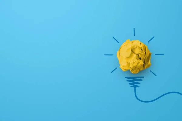 Creative thinking ideas and innovation concept. Paper scrap ball yellow colour with light bulb symbol on blue background