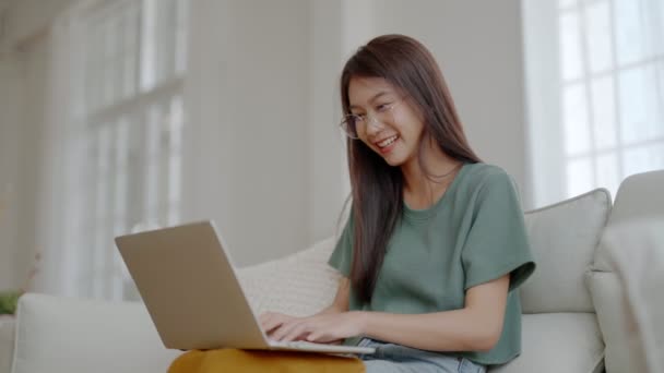自宅のノートパソコンで働く若いアジア人女性の笑顔 コンピュータ リモート スタディを使用して魅力的なアジアの女性 オンライン教育とビデオ通話を見て — ストック動画