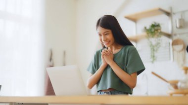 Asyalı bir kadının kazanmasını ya da bilgisayar laptopunda ecommerce alışveriş teklifi almasını kutlayan komik bir coşku. Heyecanlı mutlu kız kazanan başarıyı kutlayan deftere bakıyor.